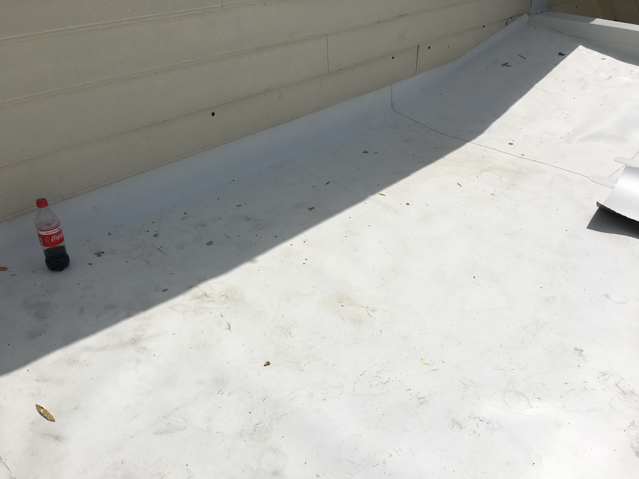 This is a view of the white TPO membrane roof that meets the wall of the shingle roof.