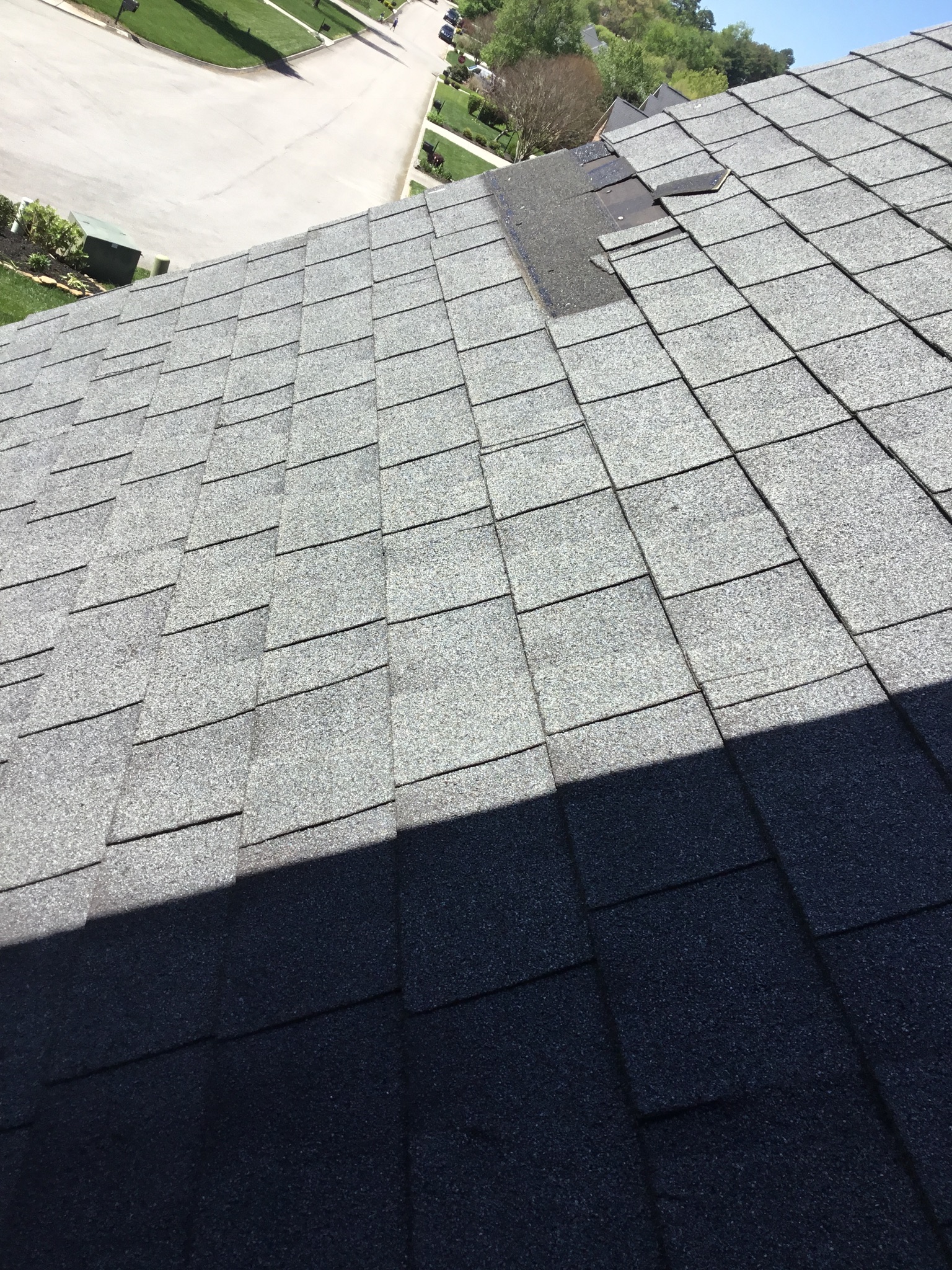 This is a view of the shingles on the roof with a section that has fallen off.