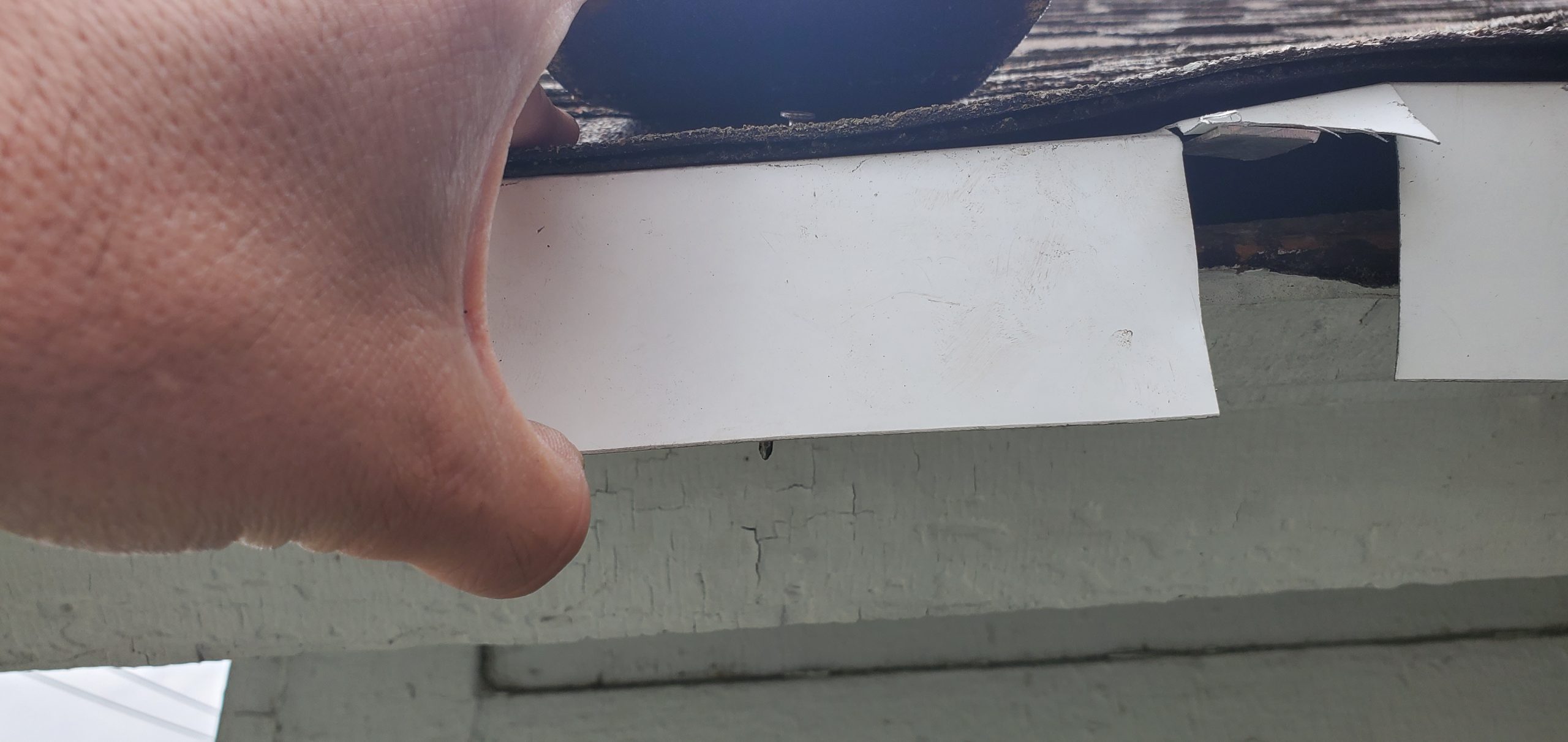 A close up view of white drip edge with the incorrect nails used on this roof. 