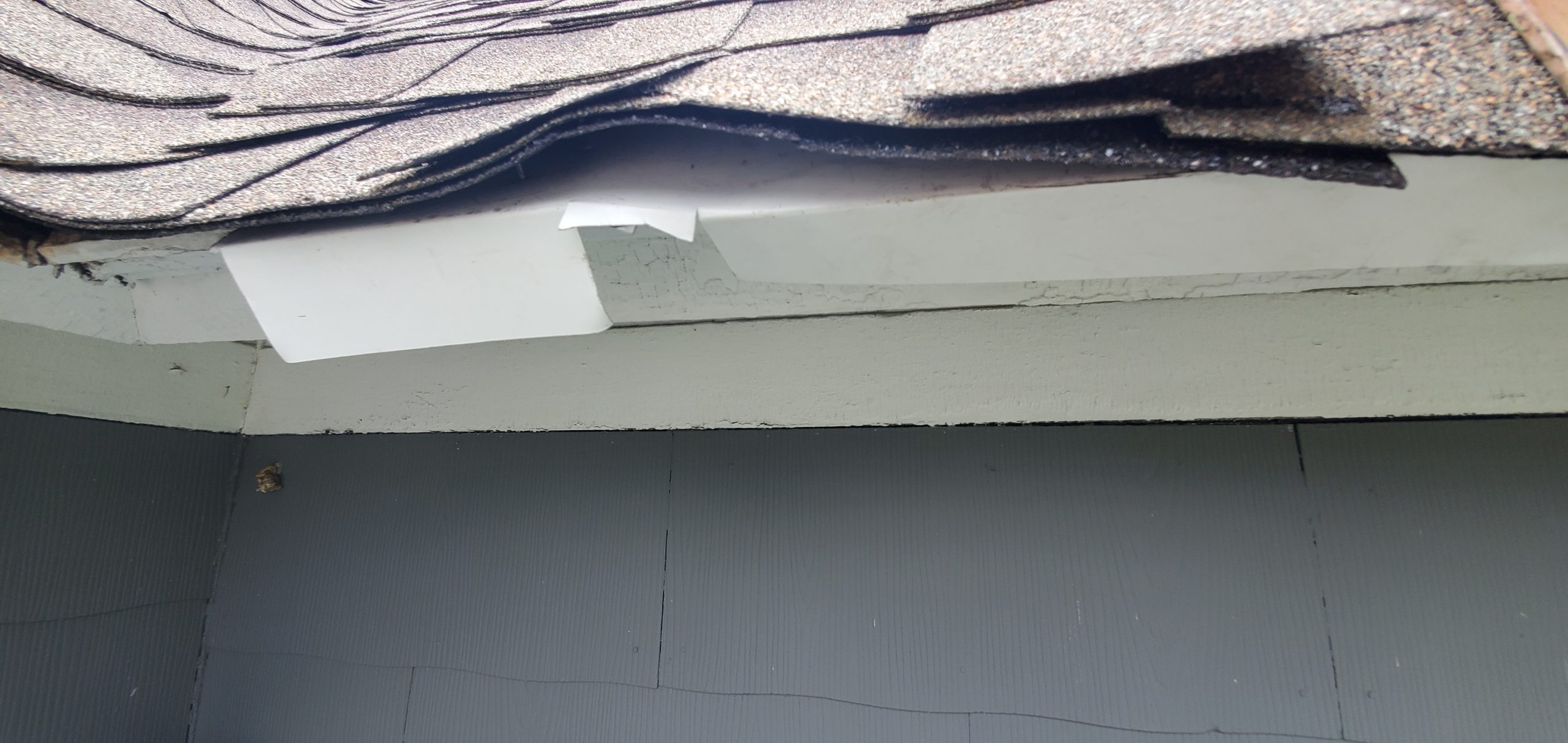 This a close up view of white drip edge that is not correctly installed. 