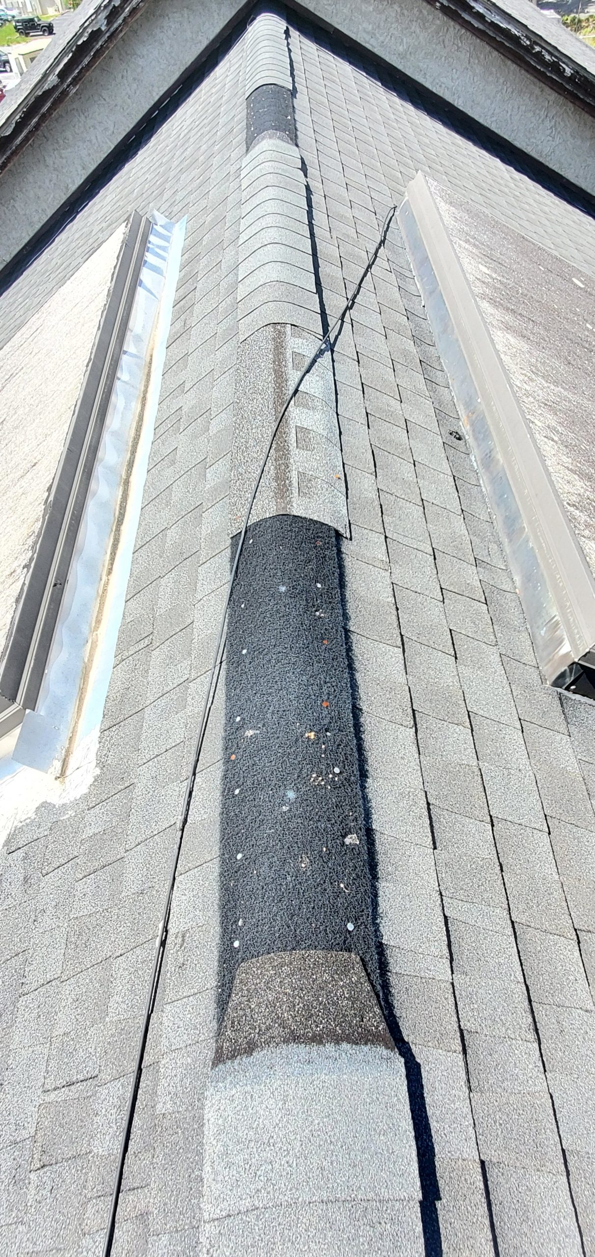 An up close view of the missing ridge cap shingles on the ridge of the roof. 