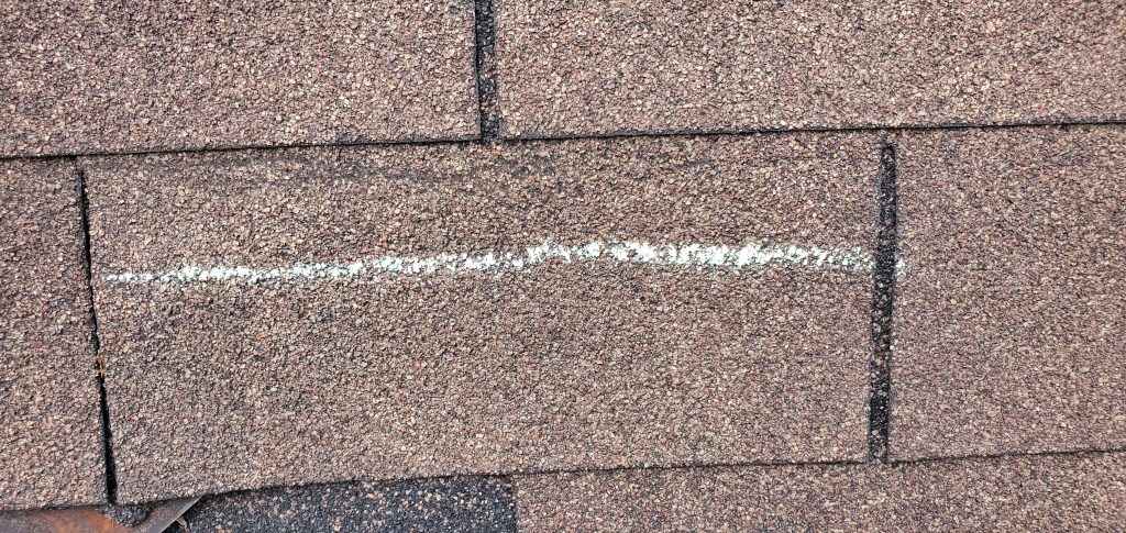 this is a picture of a wind creased shingle that is considered storm damage