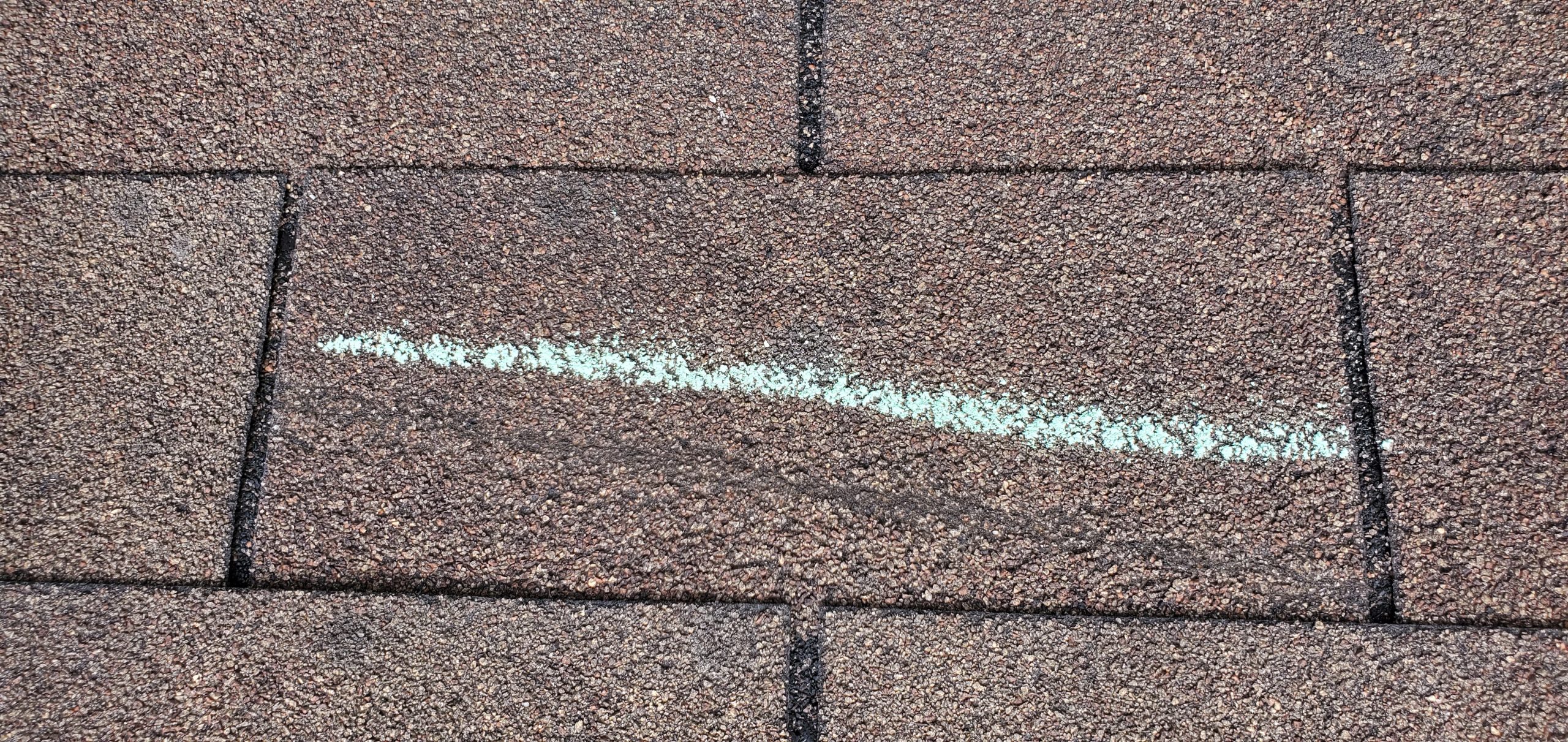 this is a picture of a storm damaged shingle it is storm damaged from the wind