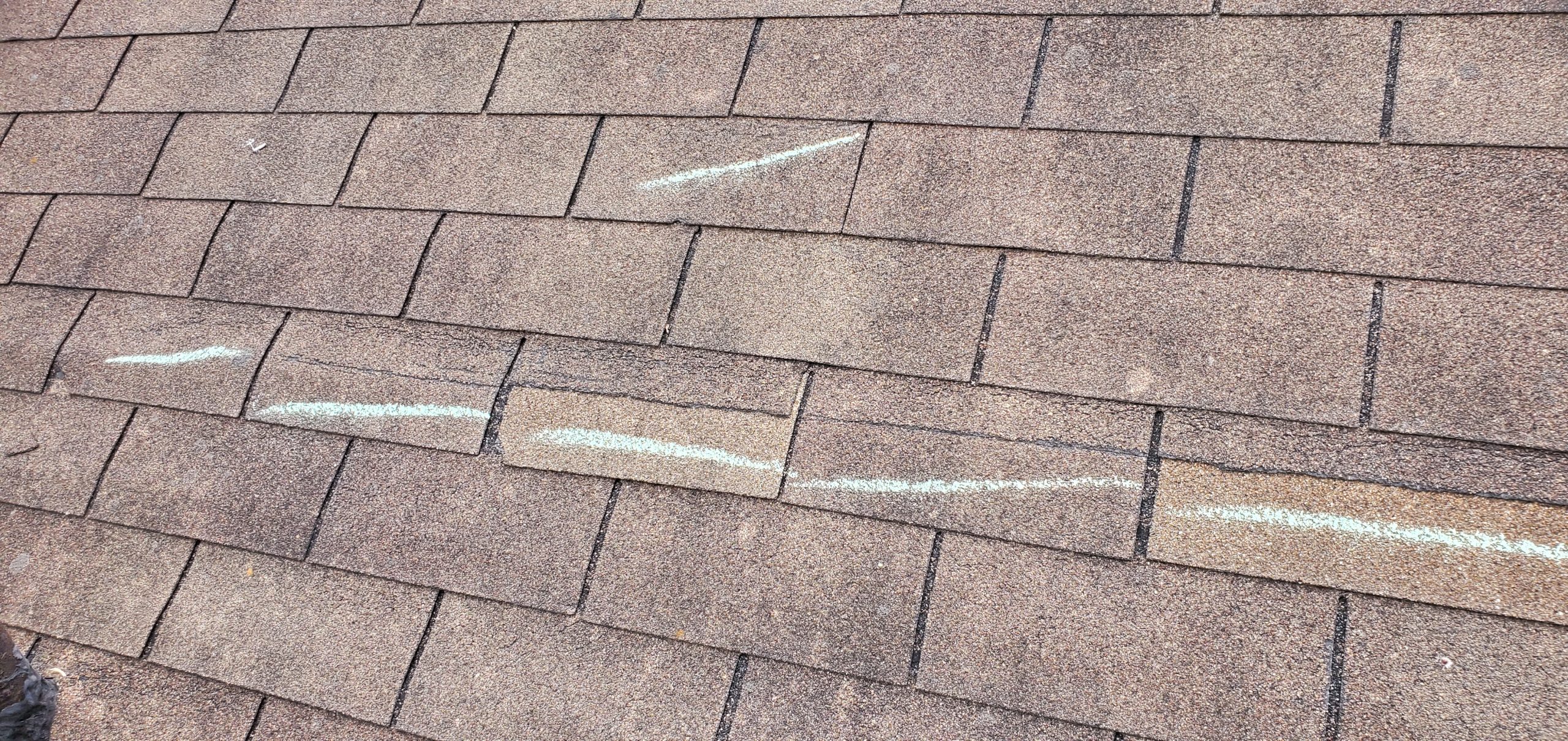 this picture shows some sort of a cut along several roofing shingles