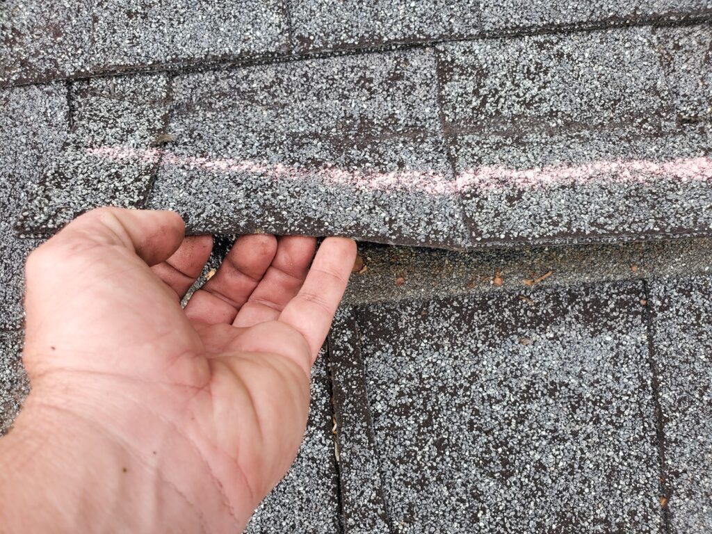 another wind creased shingle that is marked for an insurance adjuster to see
