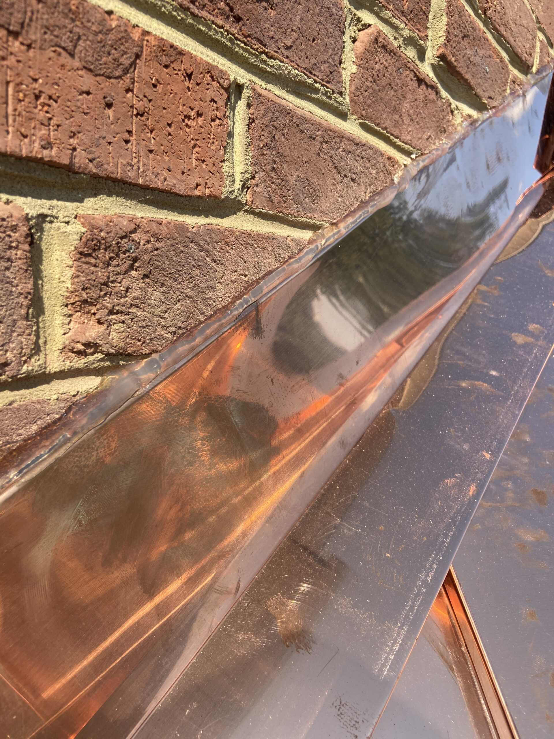 Shiney copper metal roof is sealed into bricks