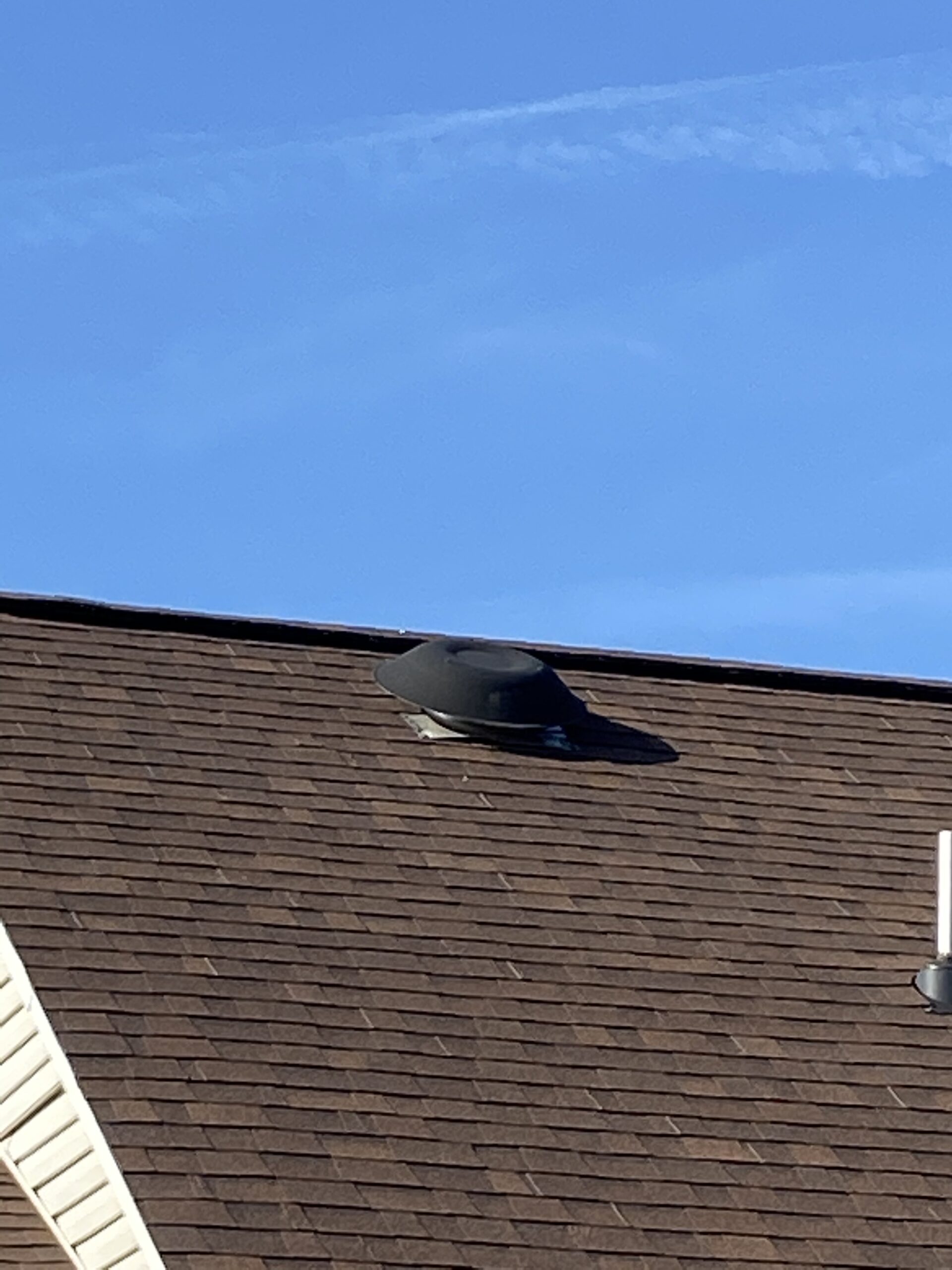 This is a picture of a brown roof with a round roof vent in it