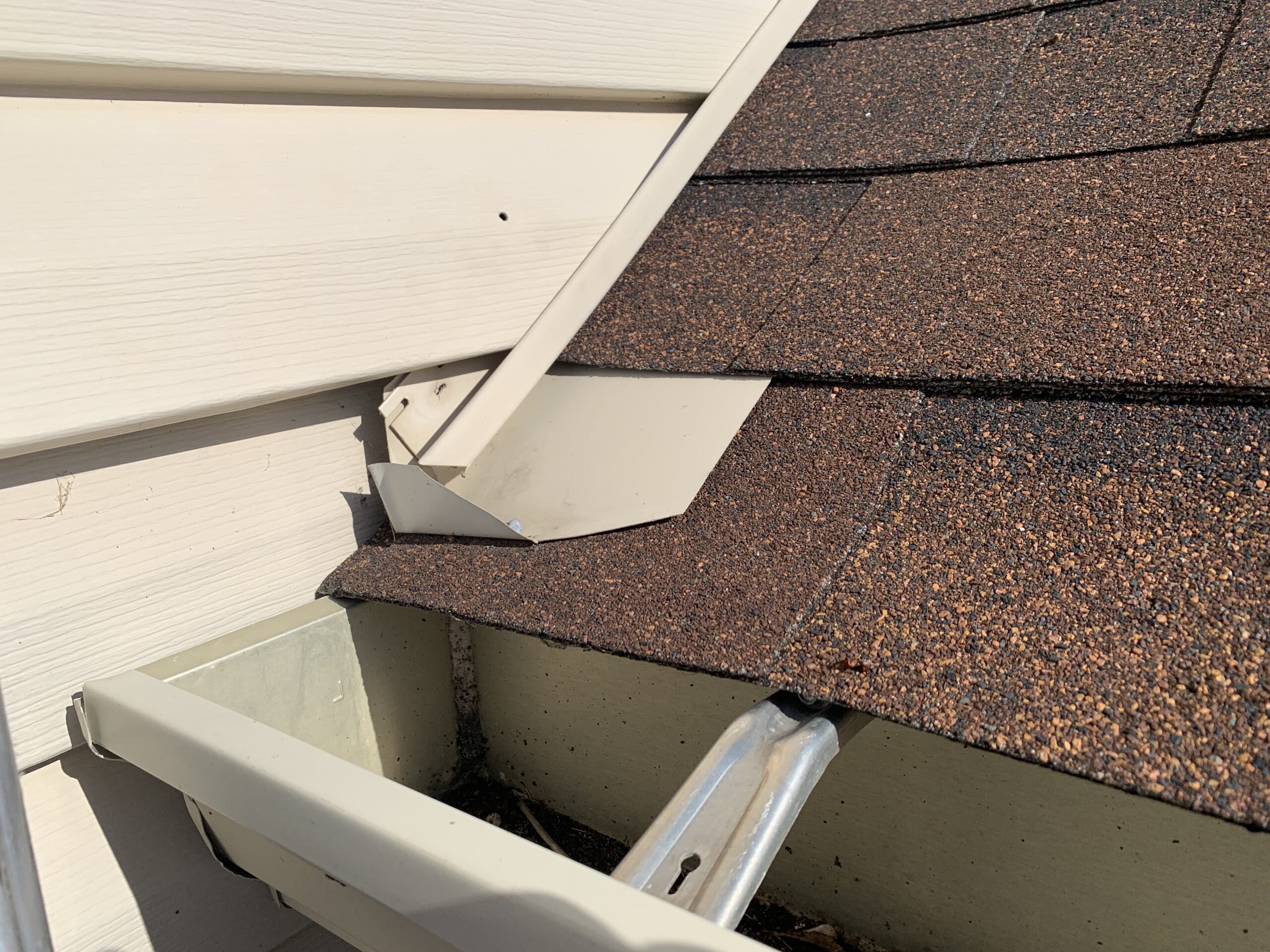 A diverter at the edge of gutter is preventing water from seeping between the endcap at the end of the gutter and the vinyl siding