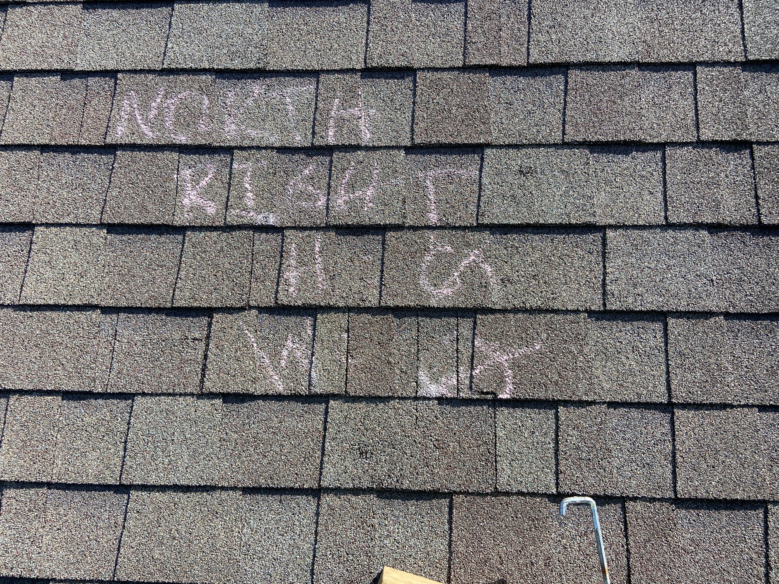 Adjuster’s chalk marks on a shingle roof saying there’s no damage to the roof