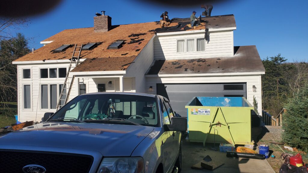 This is a picture of a roof And there are guys  on top of it removing the shingles