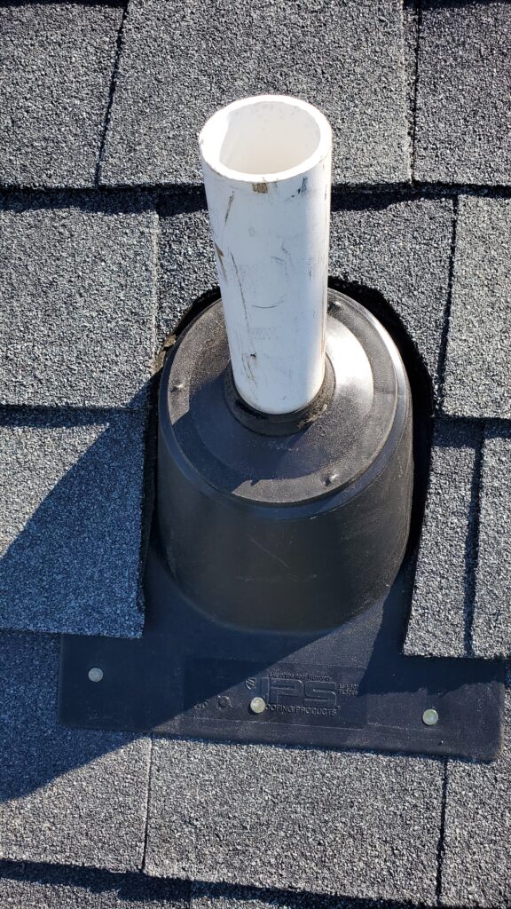 This is a picture of a black pipe boot around a wite pipe on a shingle roof 