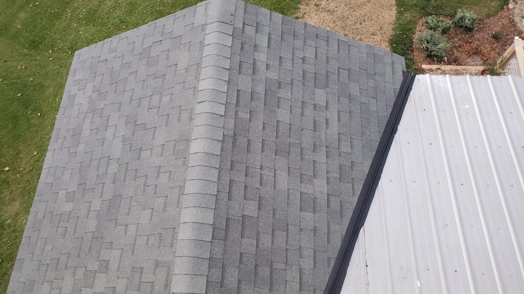 This is a picture of shingle roof that runs into a metal roof. The metal roof is on the right and the shingle roof on the left