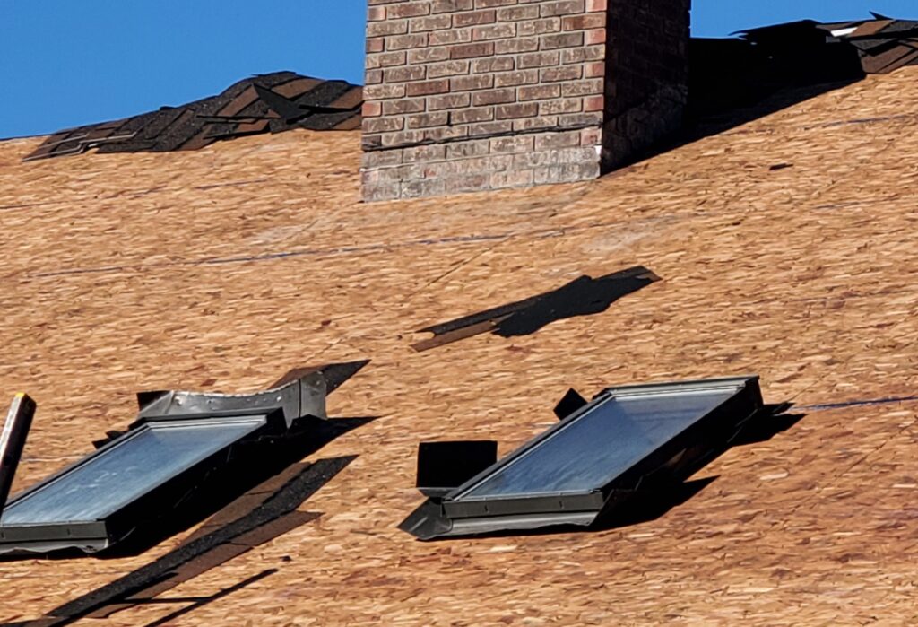  This is a picture of a roof without shingles and 2 old skylights that are about to be removed 