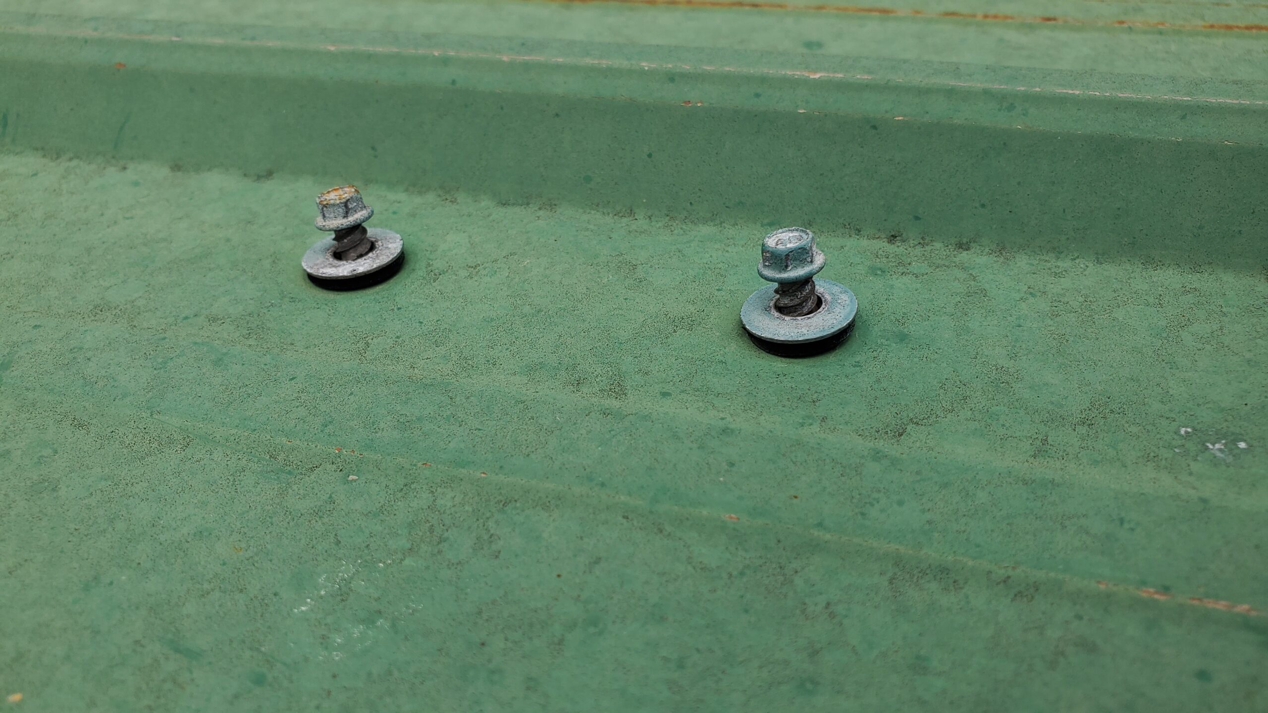 This is a picture of screws on a green metal panel.