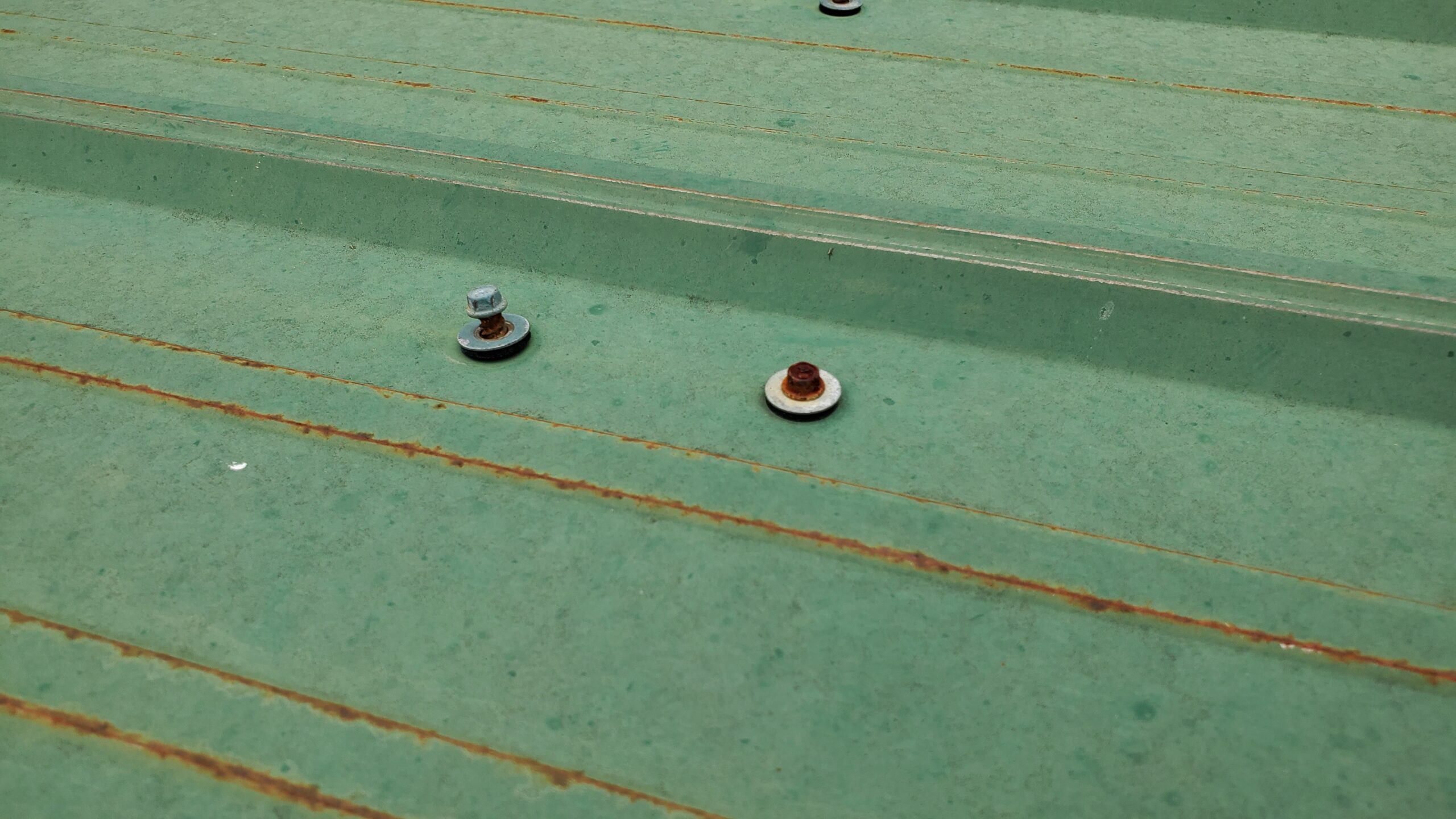 This is a picture of a loose screw on a green metal panel with rust. 