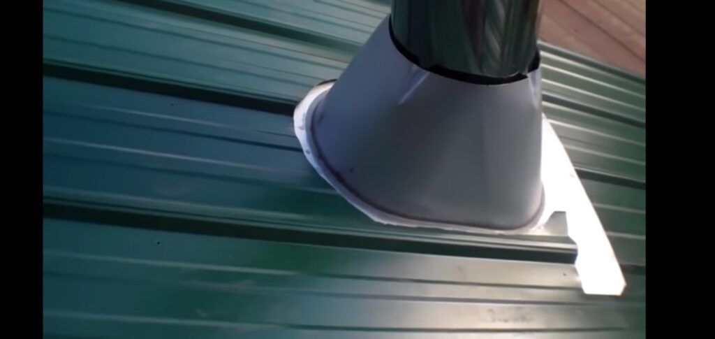 This is a picture of a metal chimney vent coming through a green metal roof. This is the proper way to install it with the top under the metal.