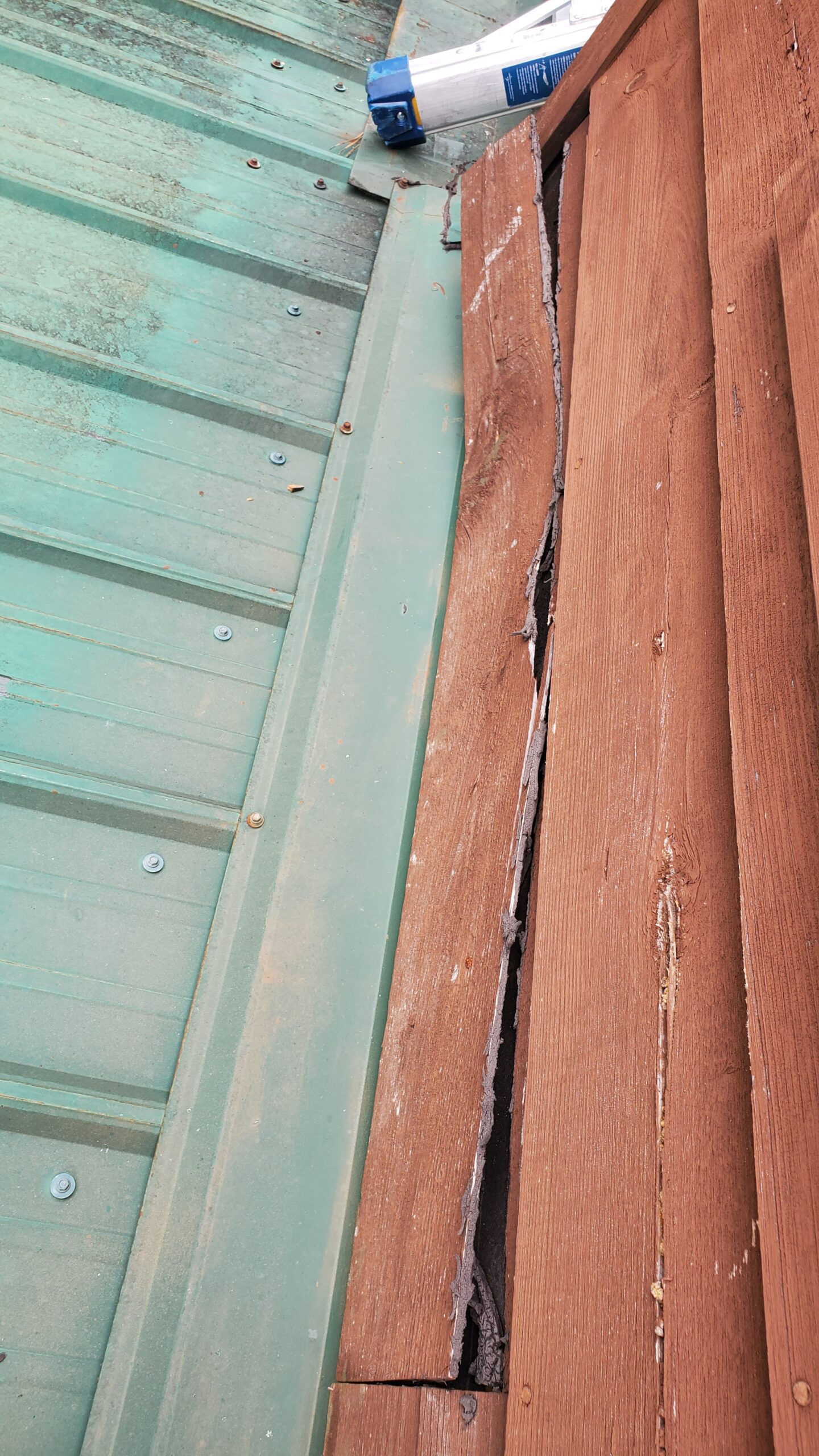 This is a picture of Brown siding that is starting to break in crack apart