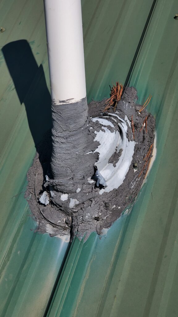 This is a picture of a plumbing pipe boot that is covered in roofing cement. Its on a green metal roof