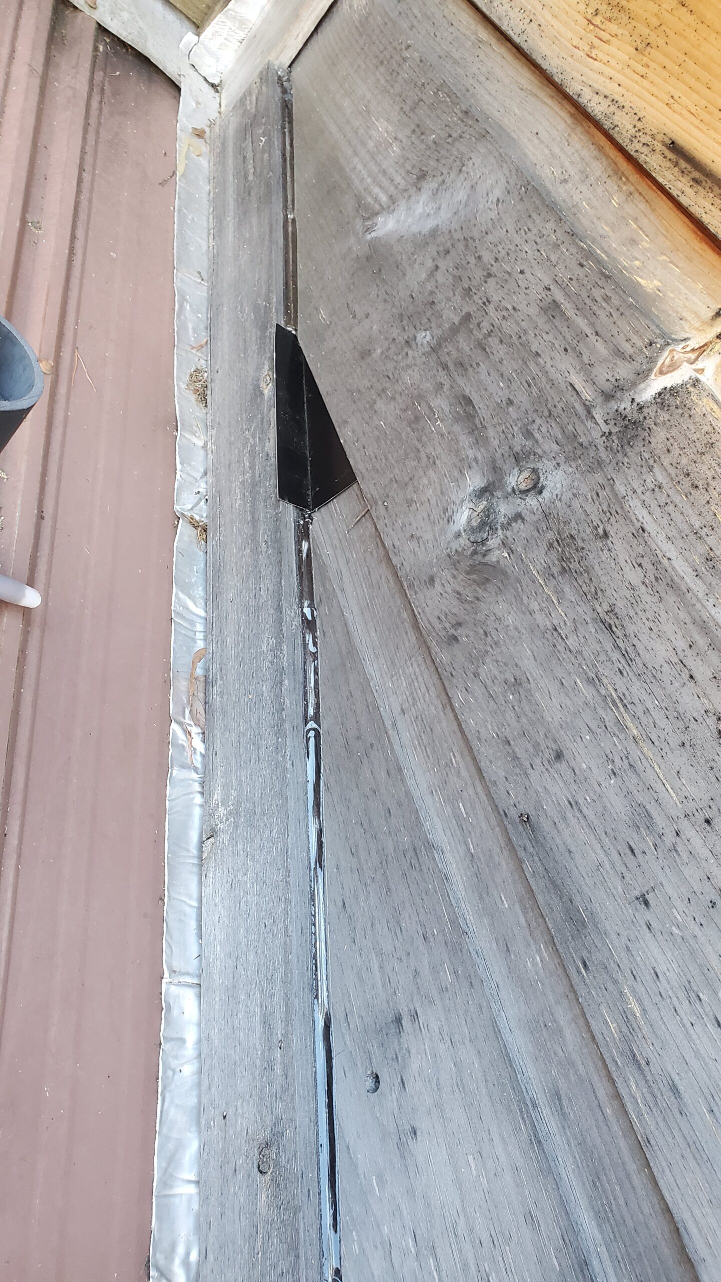This is a picture of a piece of triangular metal flashing between two pieces of wooden siding 