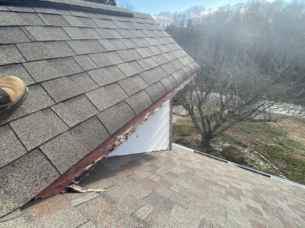 This is a picture of a white and red dormer with rotting fascia boards