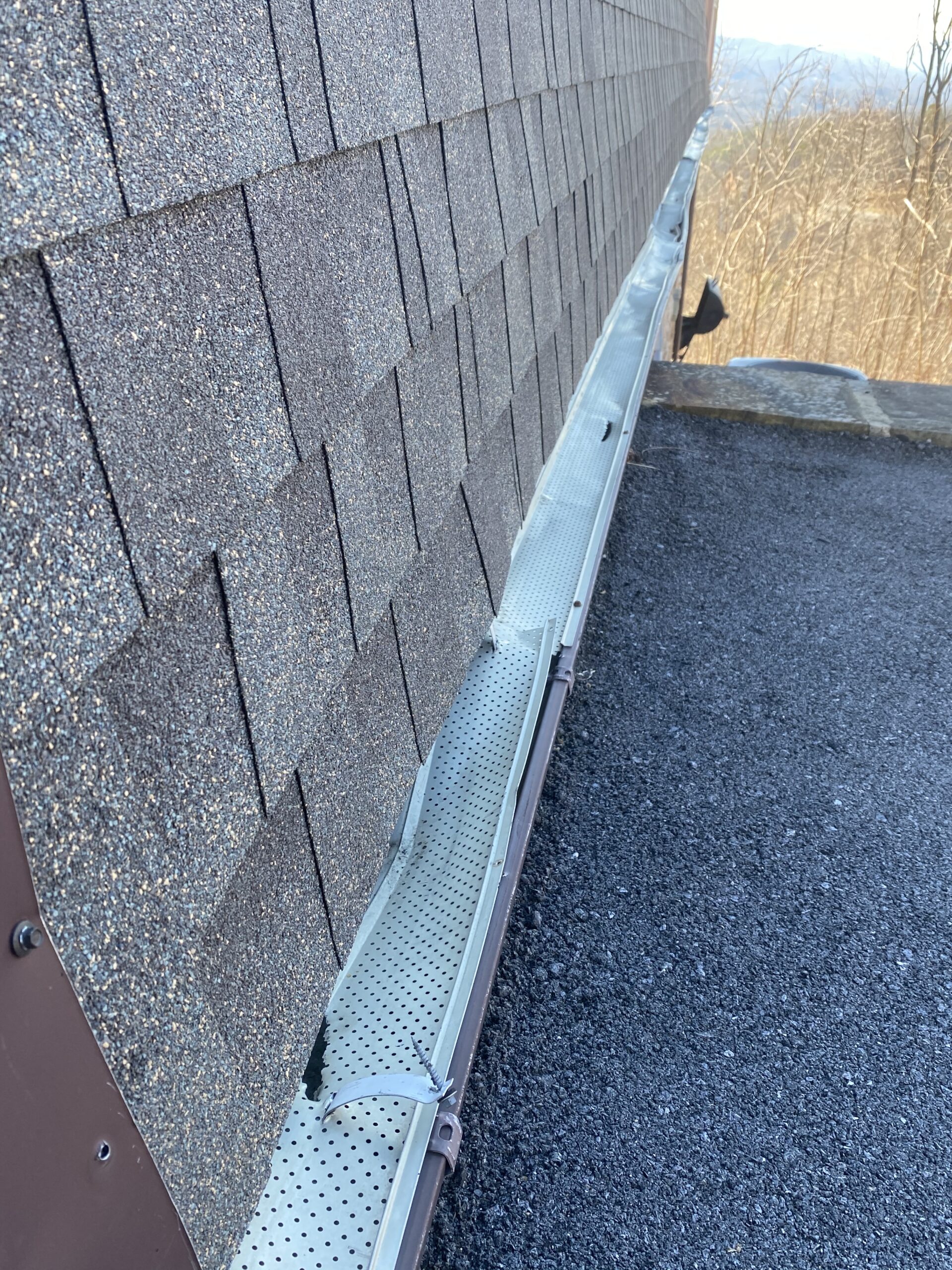 This is a picture of old gutters and gutter guards that need to be replaced