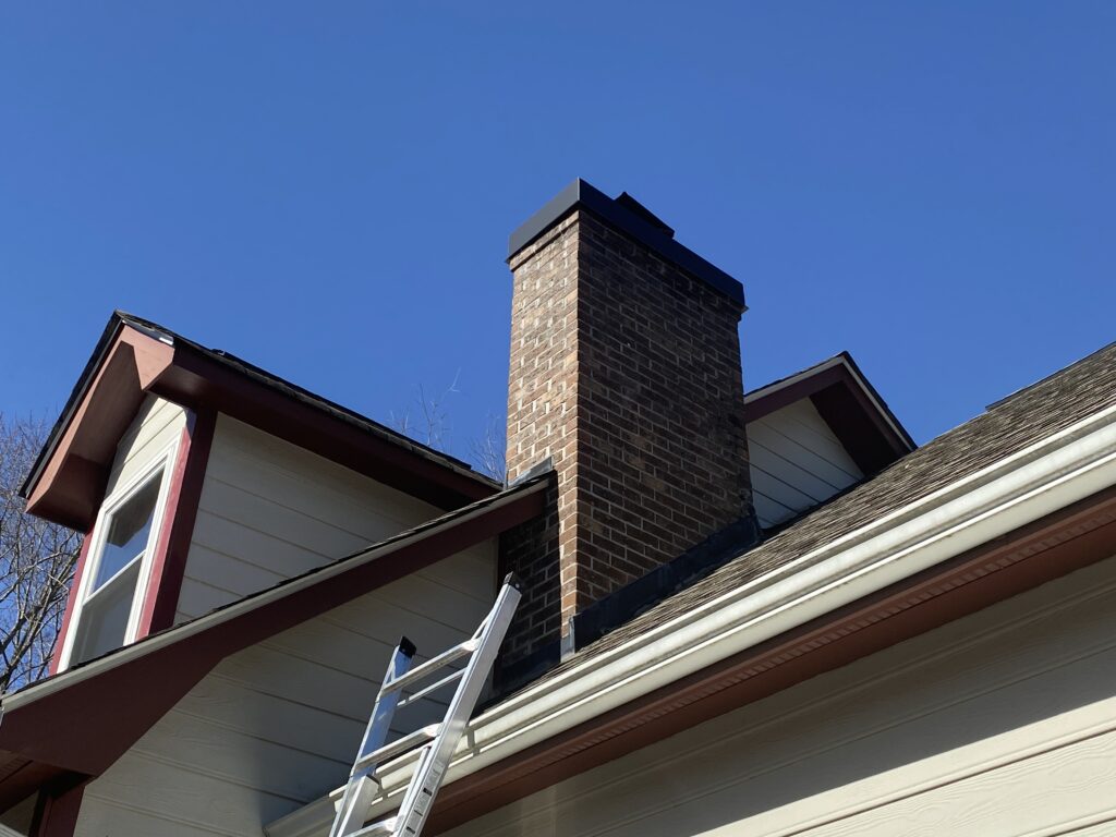 This is a picture of a white and red home with a brick chimney