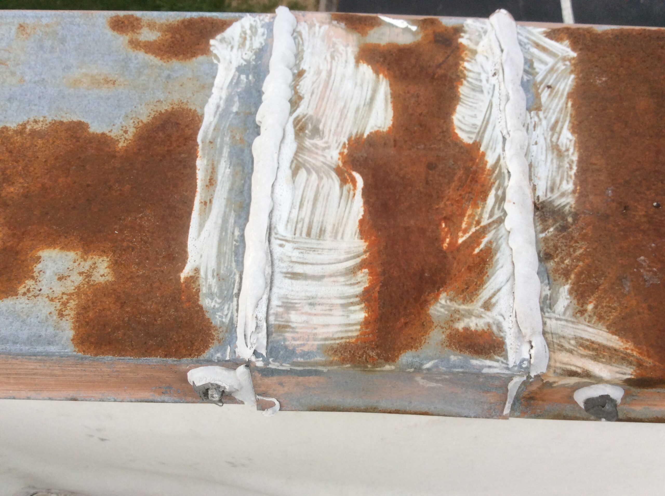 This is a view of rusted metal with white caulk to seal the laps.