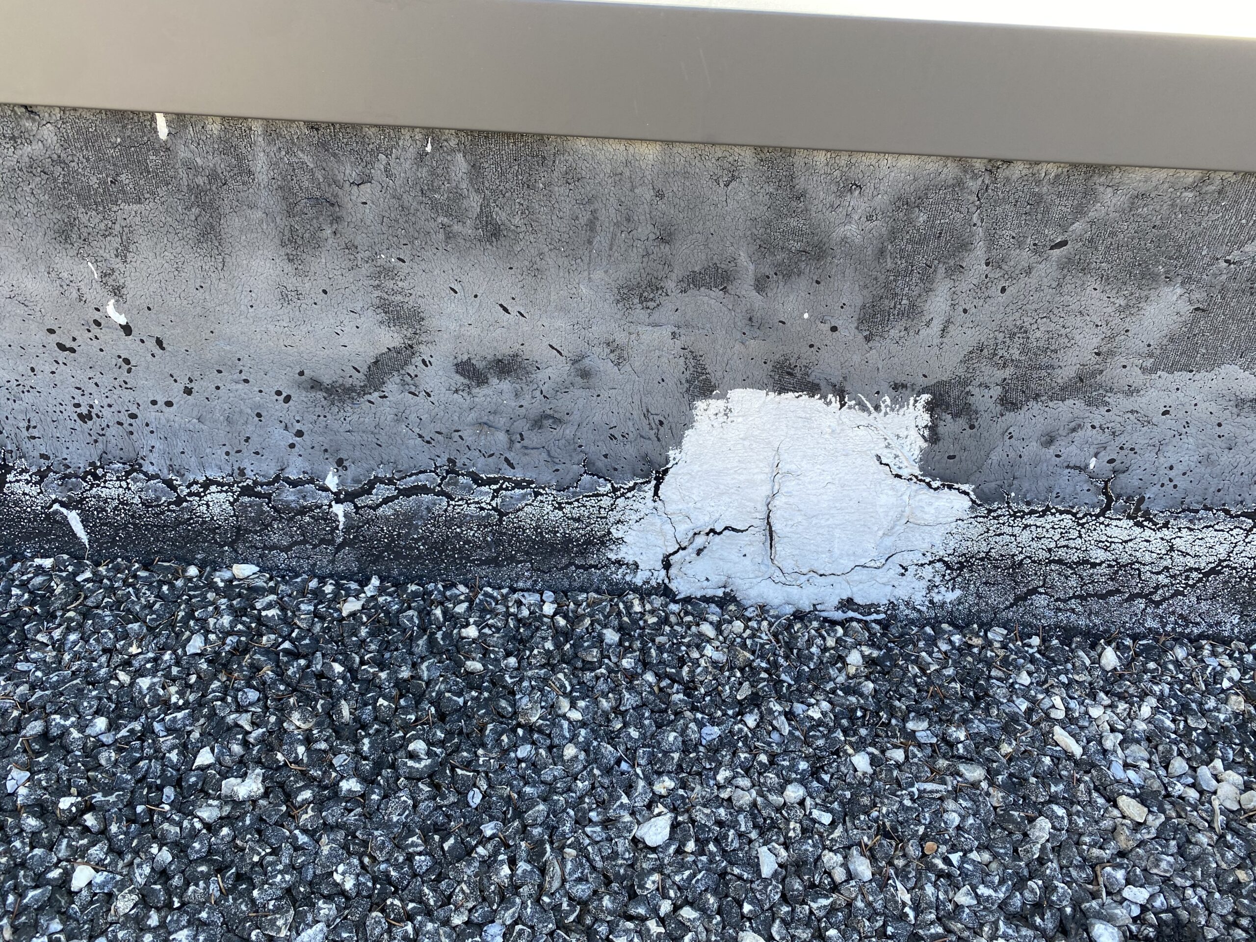 This is a picture of the edge of a wall on a commercial flat roof with damage