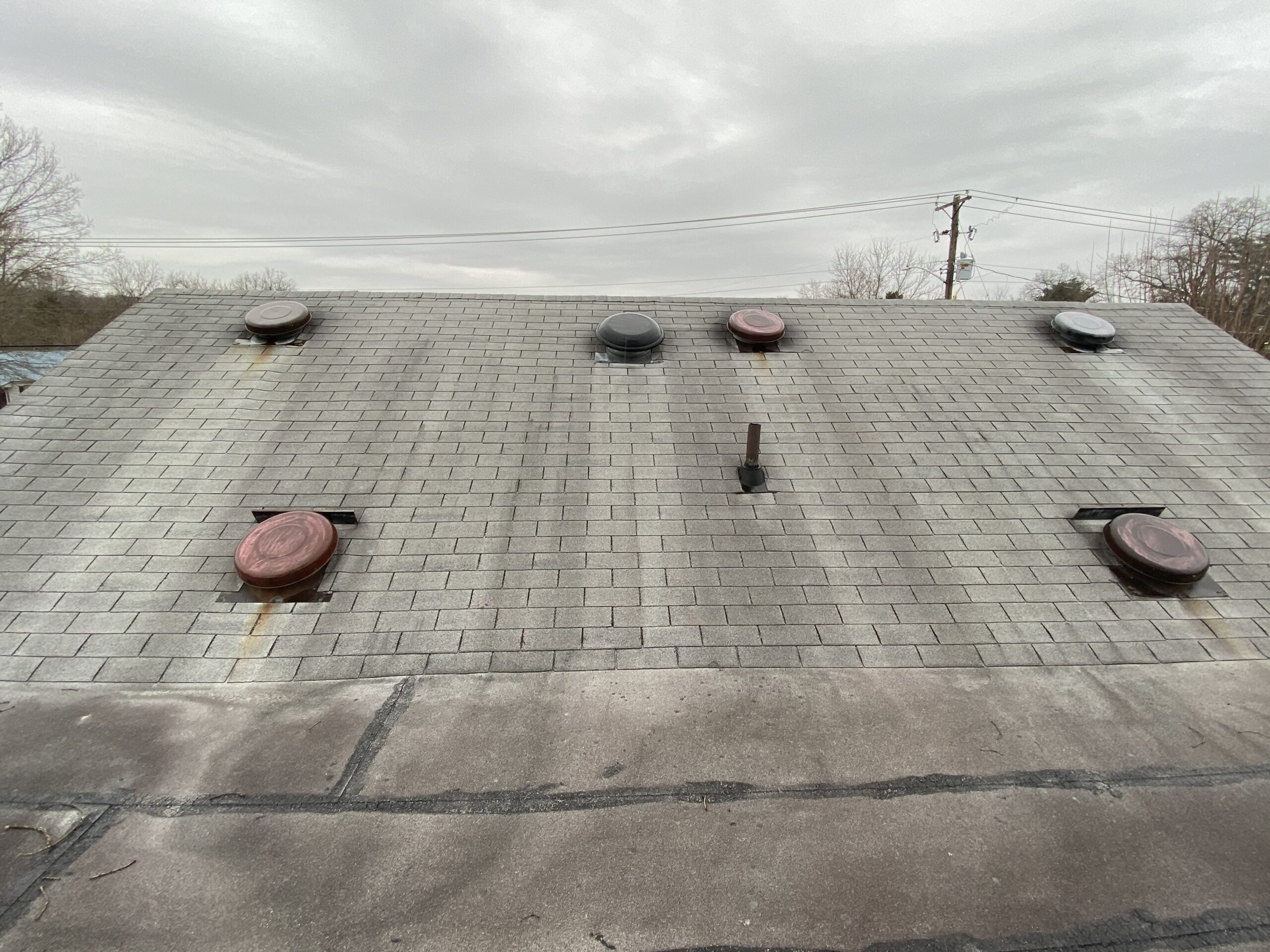 This is a picture of an old gray three tab roof with a flat roof