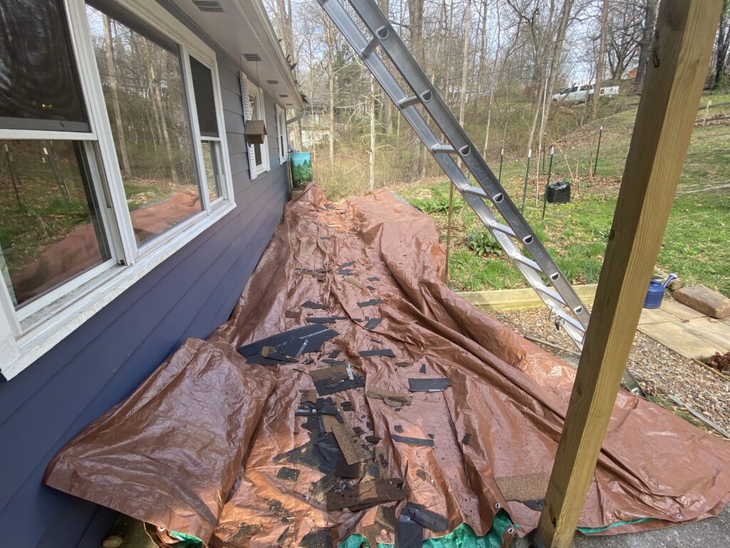 This is a picture of a brown tarp next to a blue home to protect the landscaping