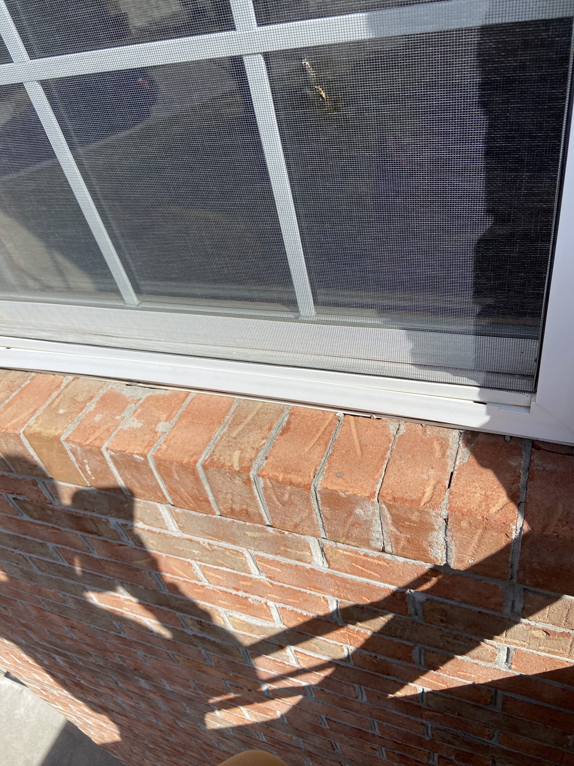 This is a picture of gaps between a window and brick siding that can cause Leaks