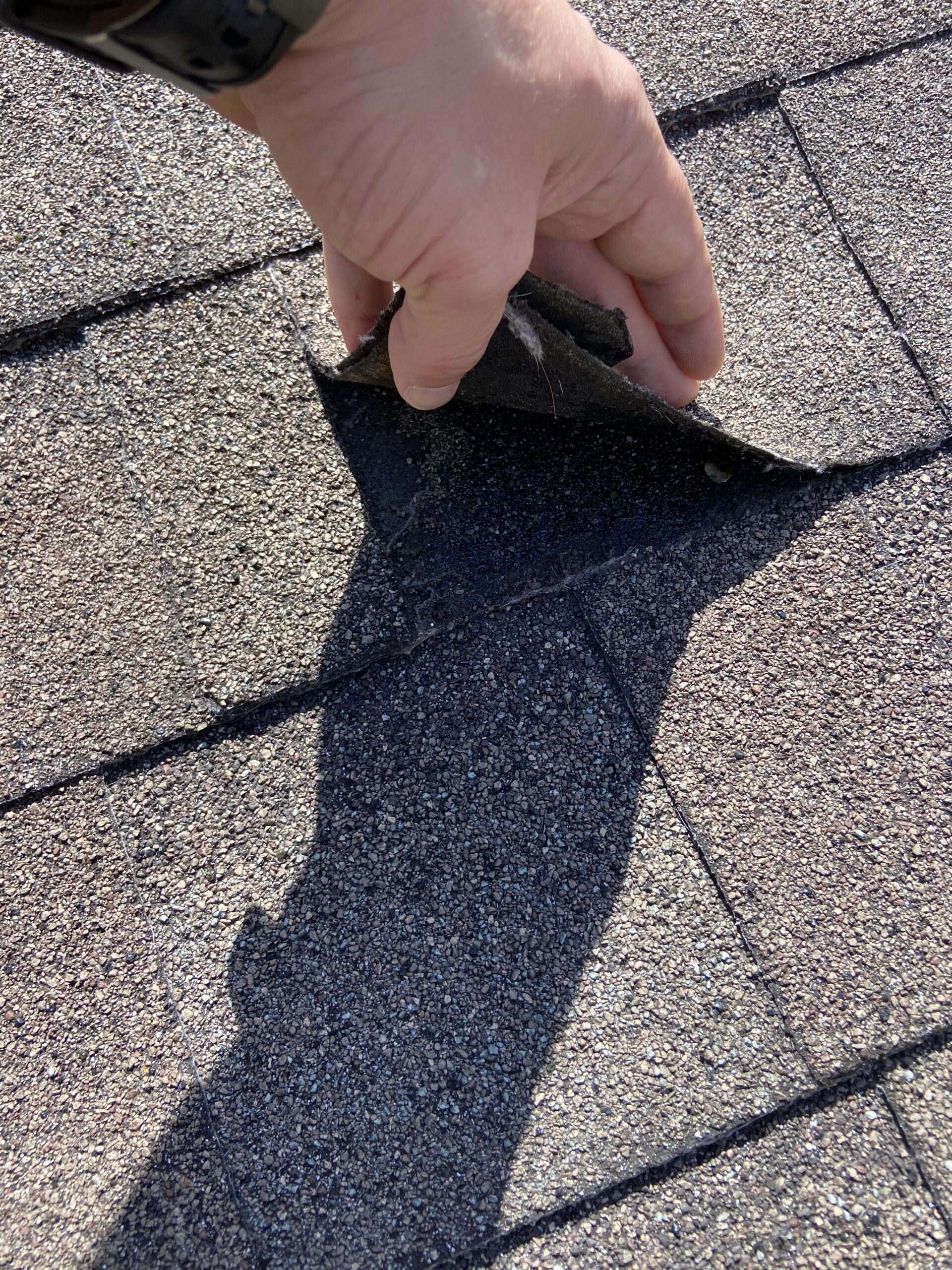 This is a picture of a nail that is misplaced too close to the union of two shingles on a roof