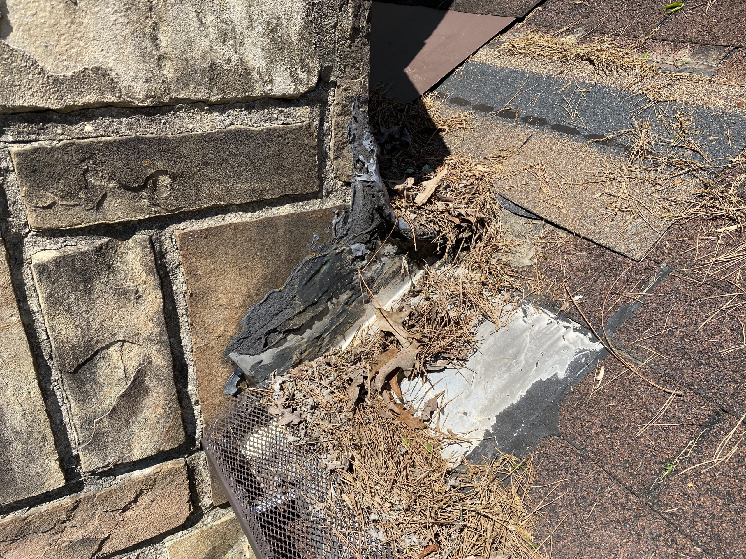 This is a picture of missing shingles and bad caulking at chimney flashing