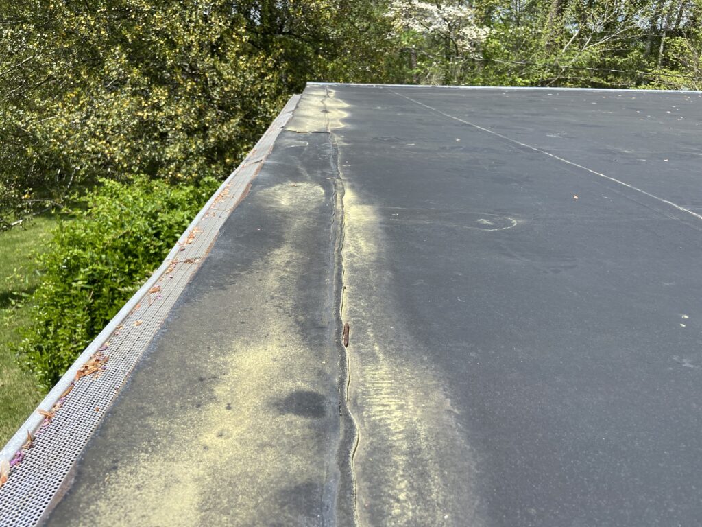 This is a picture of the edge of a rubber roof that has water that collects stands and leaks on it