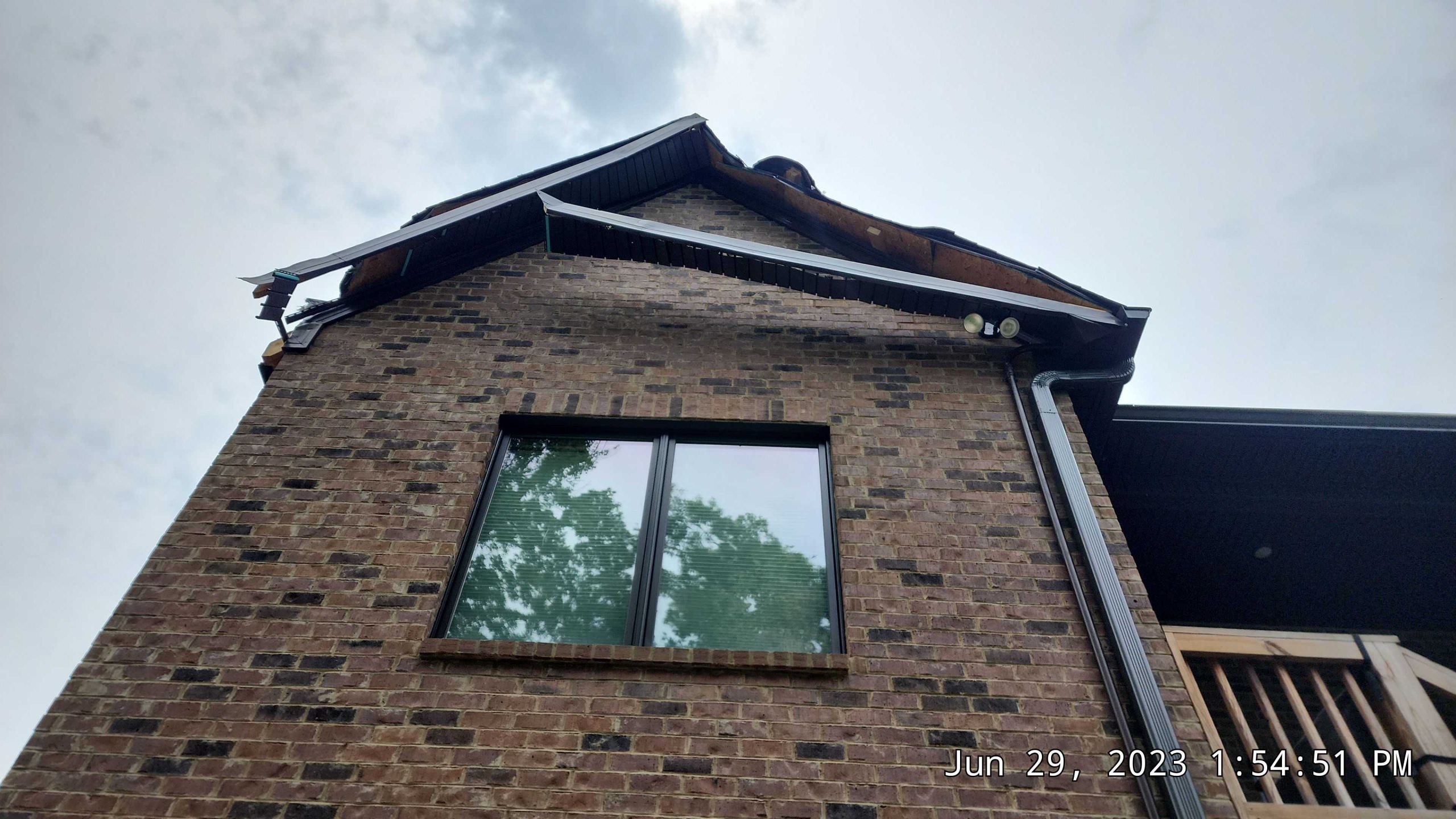 Detached gutters and damaged shingles at roof line.