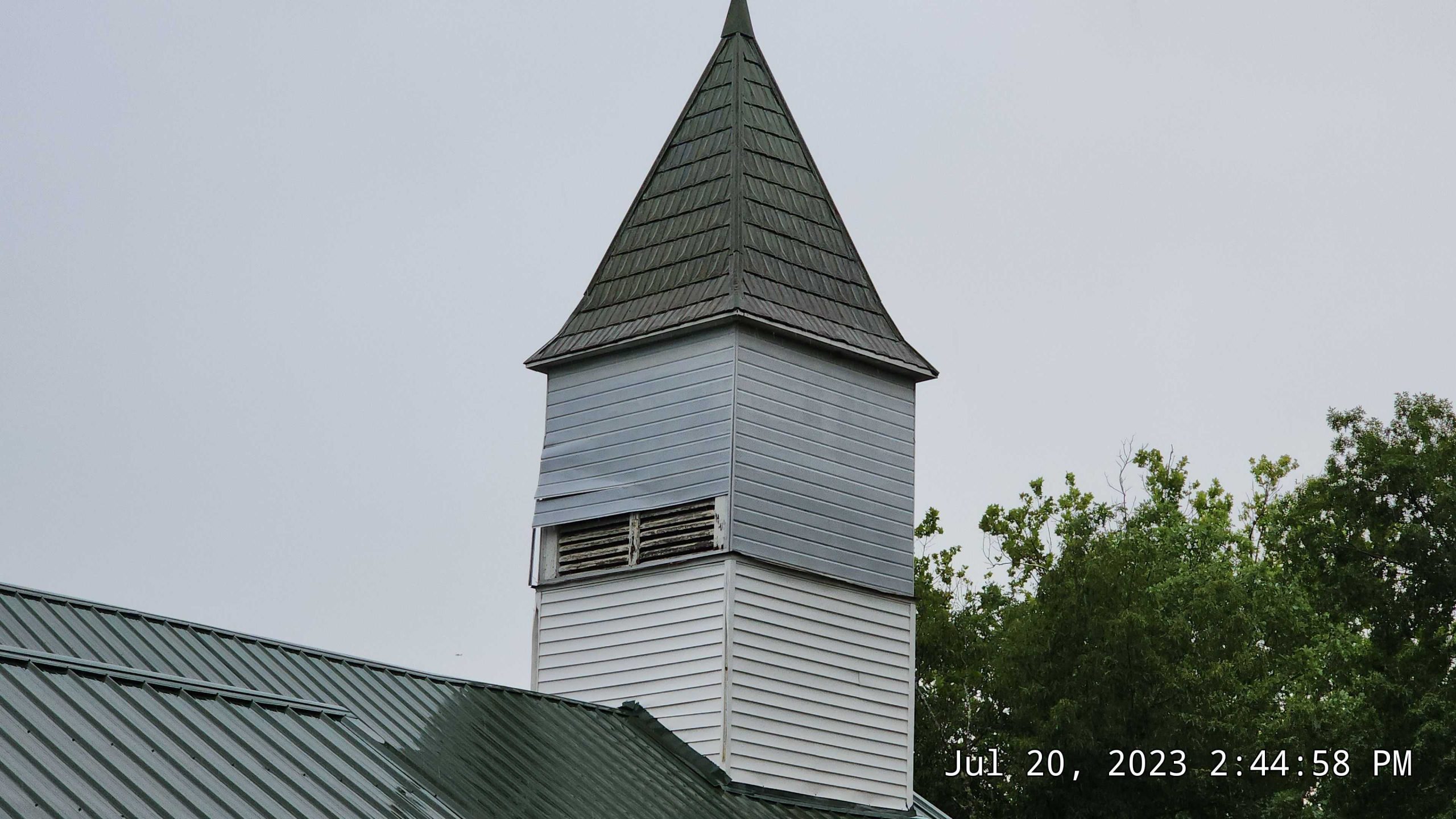 Wind damage, detached metal, and exposed boards on steeple