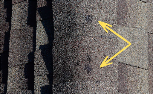 Hail damage repair, close-up of hail damage on residential roof in knoxville, severe hail damage, home showing hail damage to asphalt shingle roof, extensive hail damage on knoxville, tennessee roof, assessment of hail-damaged roof, hail damage aftermath on a knoxville roof with exposed underlayment, example of roof hail damage in Knoxville, tn for insurance claim