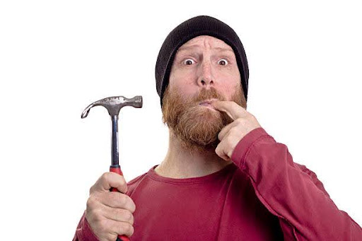 man hits finger with hammer isolated on white background